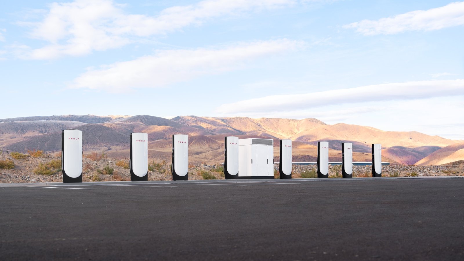 Row of Tesla V4 Superchargers against a mountain landscape