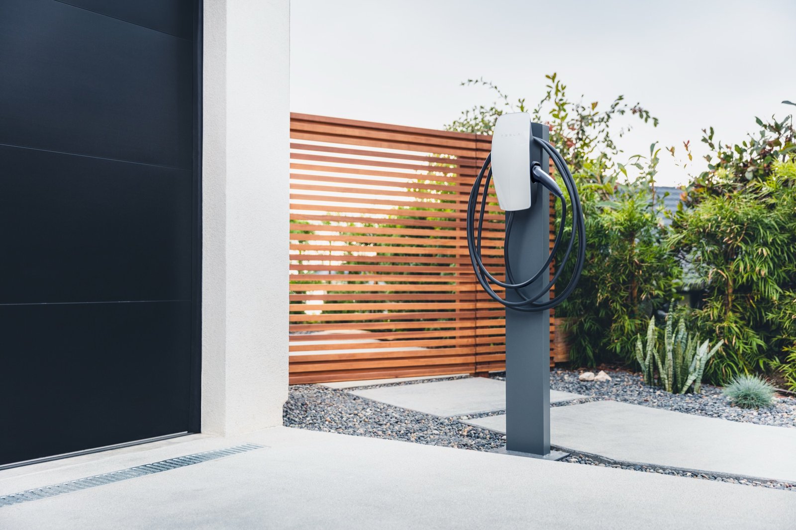 Tesla Wall Connector instalado en un pedestal junto a la entrada de un garaje