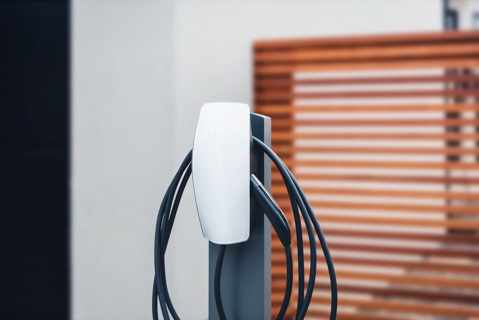 Tesla Wall Connector mounted on a garage wall next to a Tesla Model 3